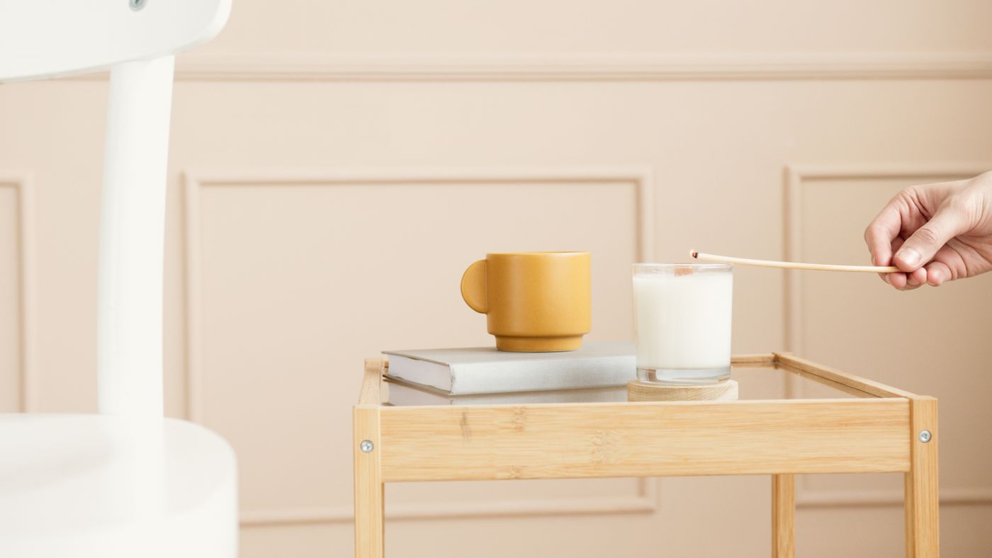 Candle, tumbler and books on a wooden side table