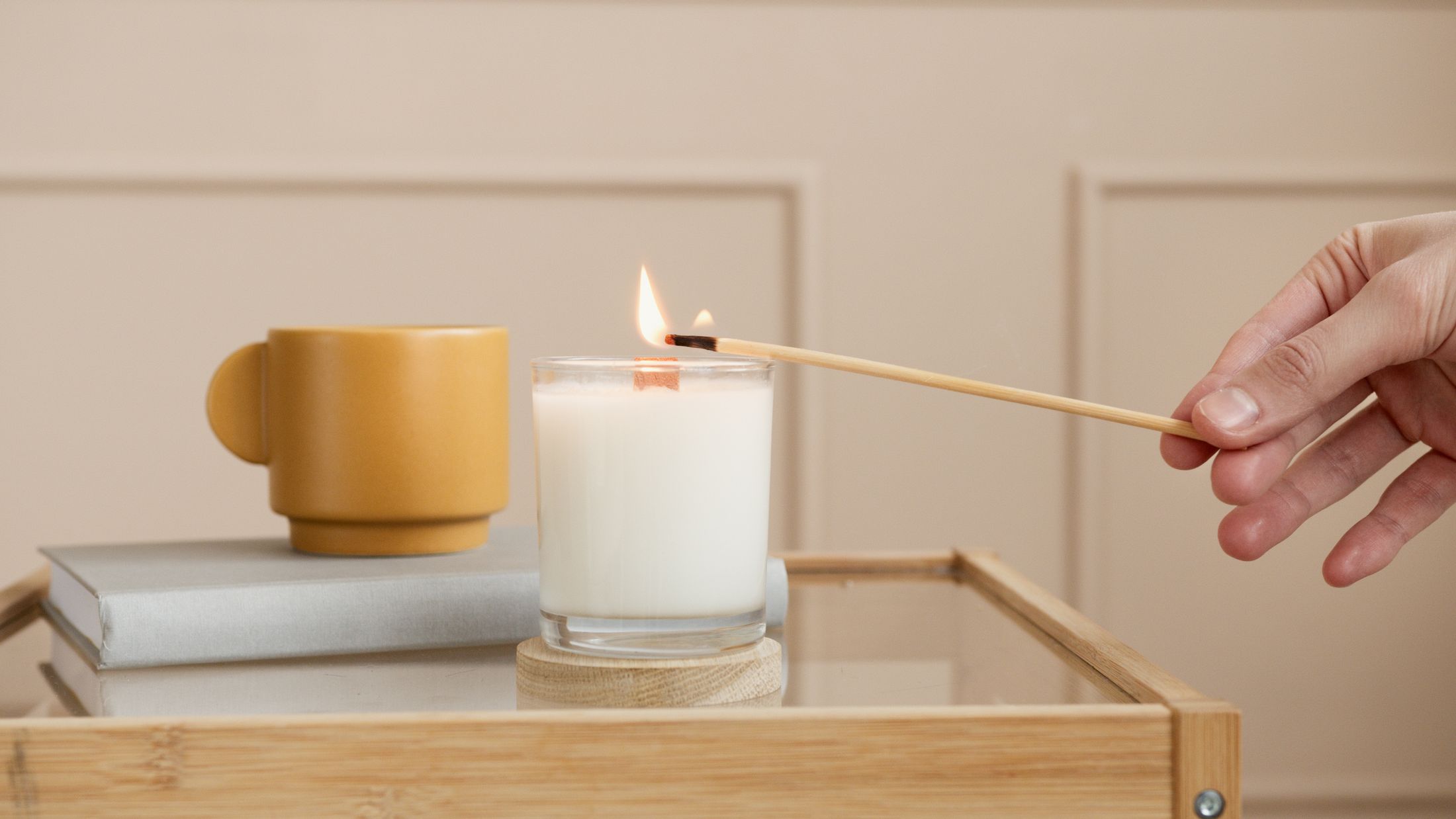 A lit candle on a small table beside cushions